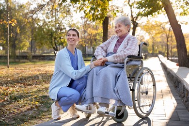 Caregiver with elderly woman in wheelchair at park