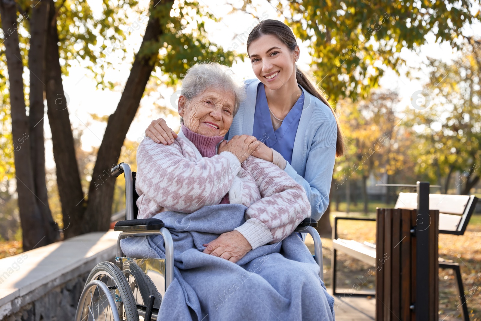 Photo of Caregiver with elderly woman in wheelchair at park