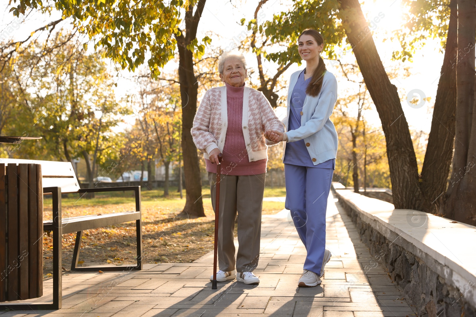 Photo of Elderly woman with walking cane and her caregiver in park