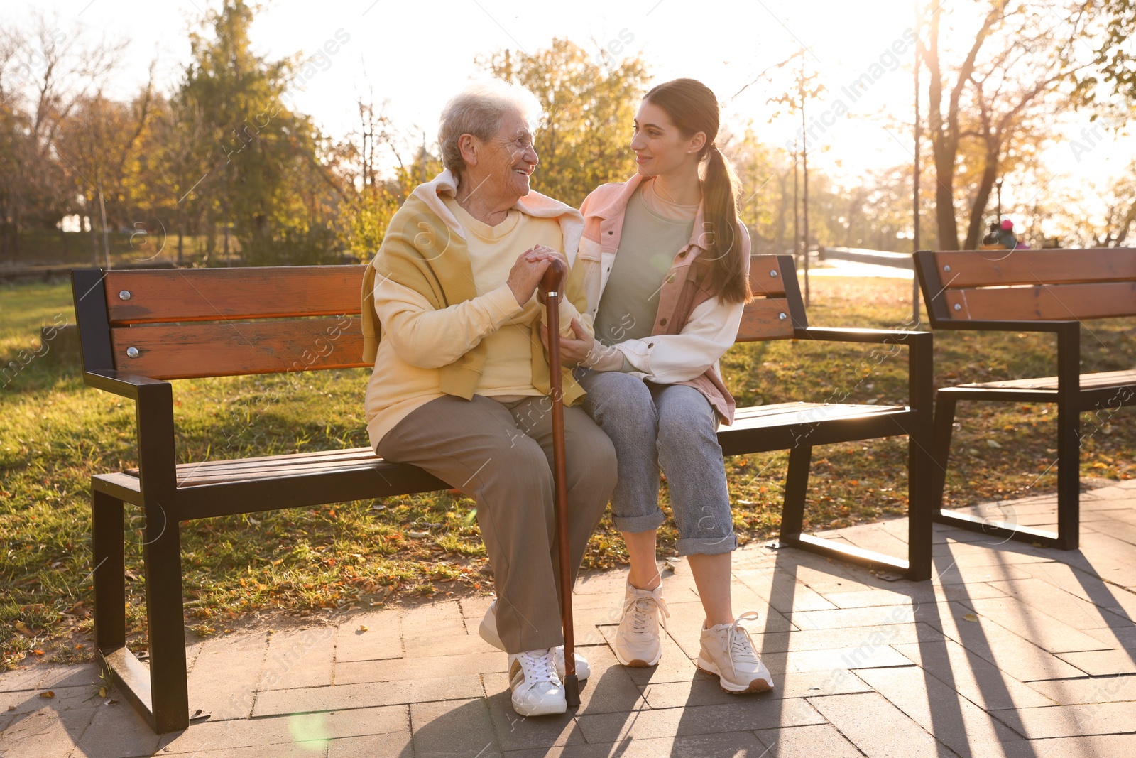 Photo of Elderly woman with walking cane and her caregiver in park