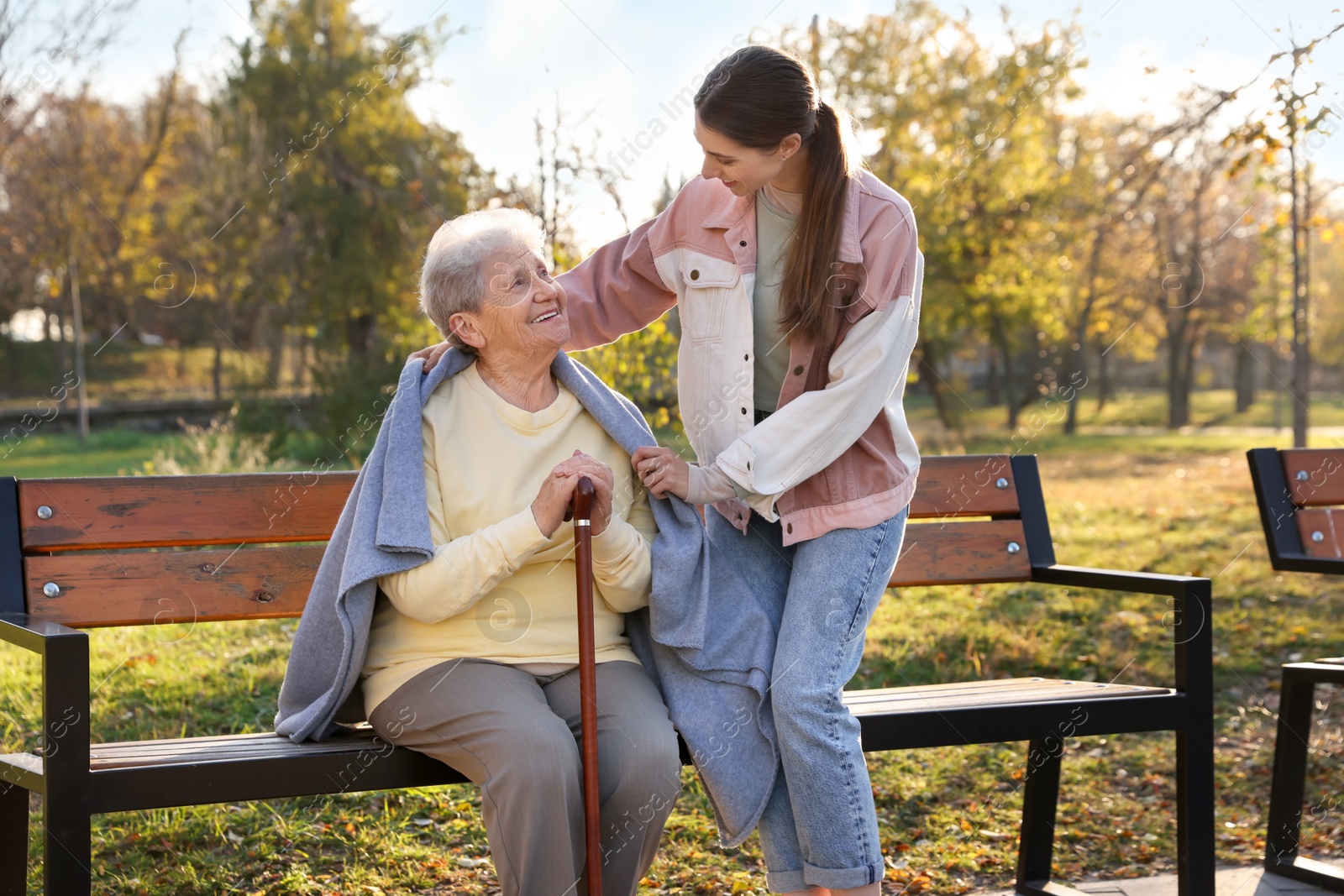 Photo of Elderly woman with walking cane and her caregiver in park