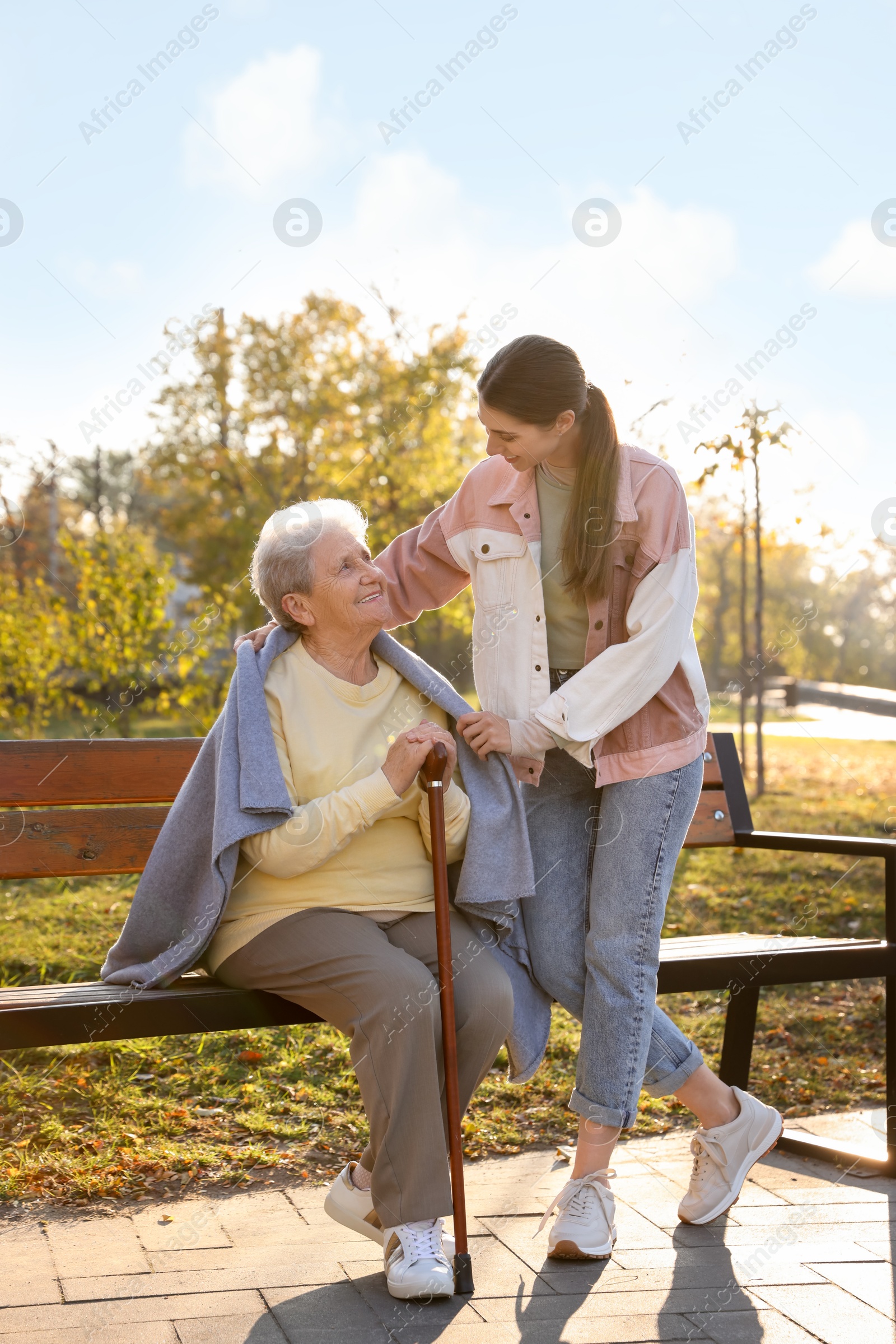 Photo of Elderly woman with walking cane and her caregiver in park