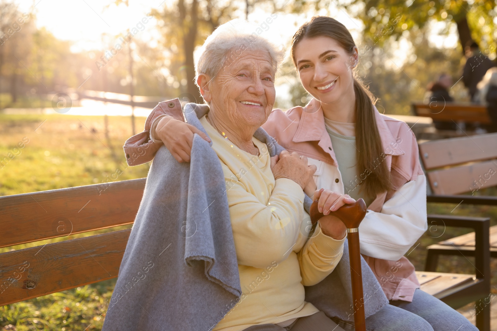 Photo of Elderly woman with walking cane and her caregiver in park