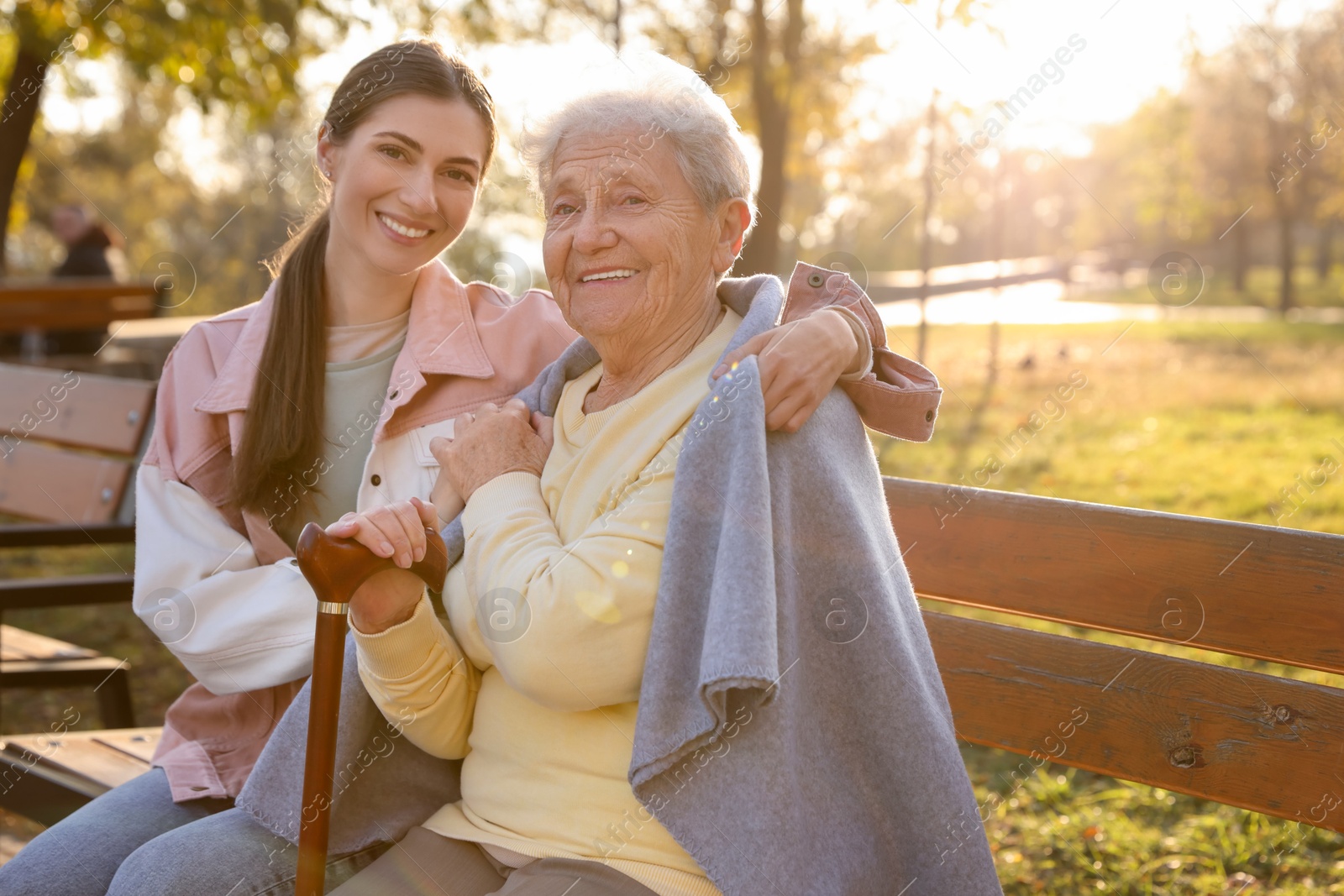 Photo of Elderly woman with walking cane and her caregiver in park