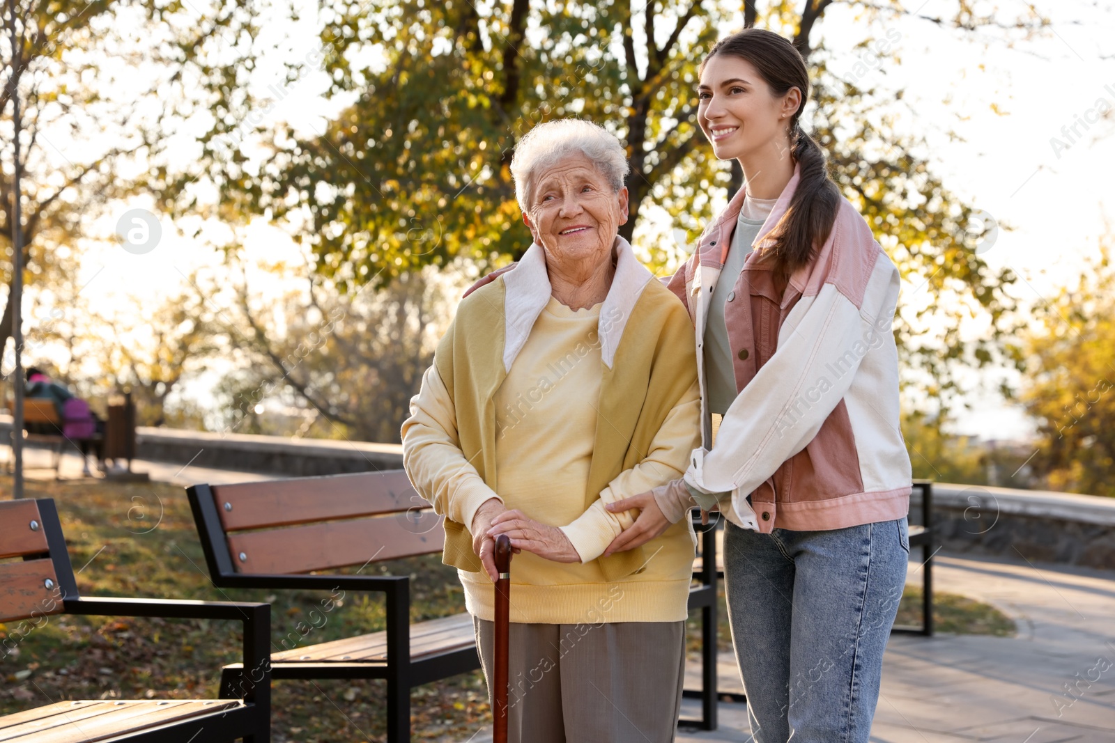 Photo of Elderly woman with walking cane and her caregiver in park