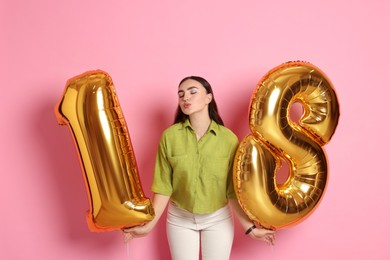 Photo of Coming of age party - 18th birthday. Happy young woman with number shaped balloons on pink background