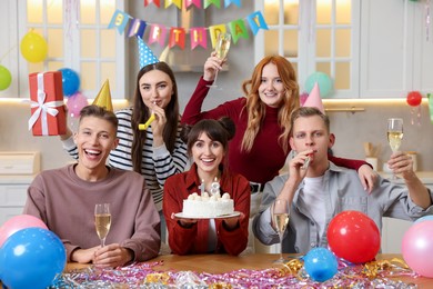 Photo of 18th birthday. Group of friends with tasty cake having coming of age party at home