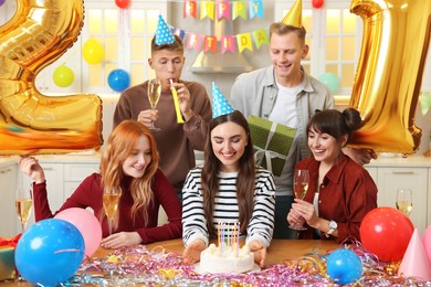 21st birthday. Group of happy friends with tasty cake having coming of age party at home