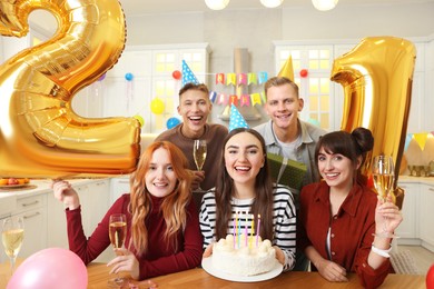 Photo of 21st birthday. Group of happy friends with tasty cake having coming of age party at home