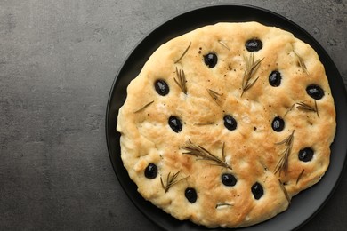 Photo of Delicious focaccia bread with olives and rosemary on grey table, top view. Space for text