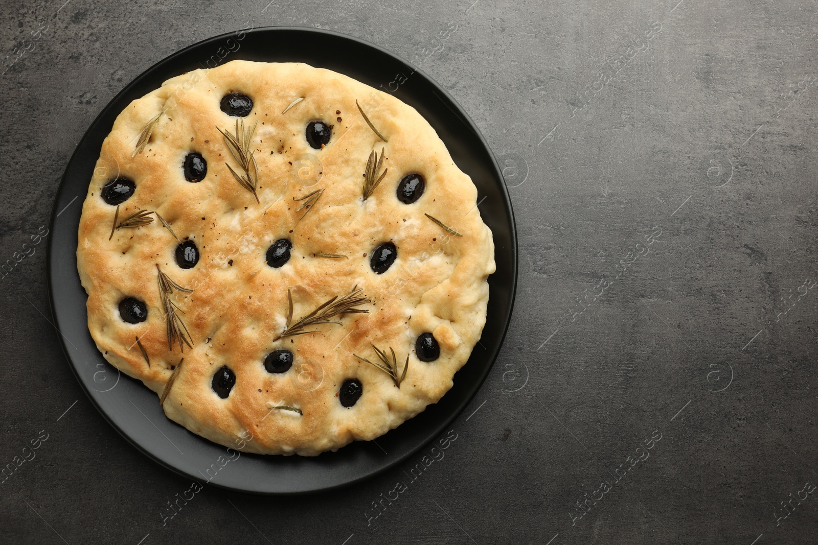 Photo of Delicious focaccia bread with olives and rosemary on grey table, top view. Space for text