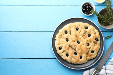 Photo of Delicious focaccia bread with olives and rosemary on light blue wooden table, flat lay. Space for text