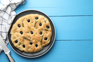 Photo of Delicious focaccia bread with olives, rosemary and knife on light blue wooden table, top view. Space for text