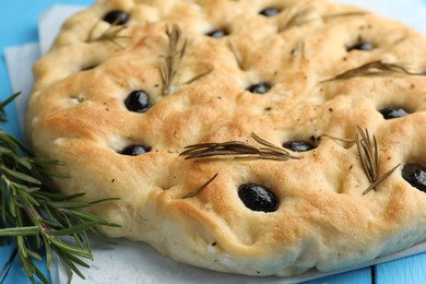 Photo of Delicious focaccia bread with olives, rosemary and salt on table, closeup