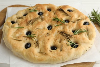 Photo of Delicious focaccia bread with olives and rosemary on table, closeup