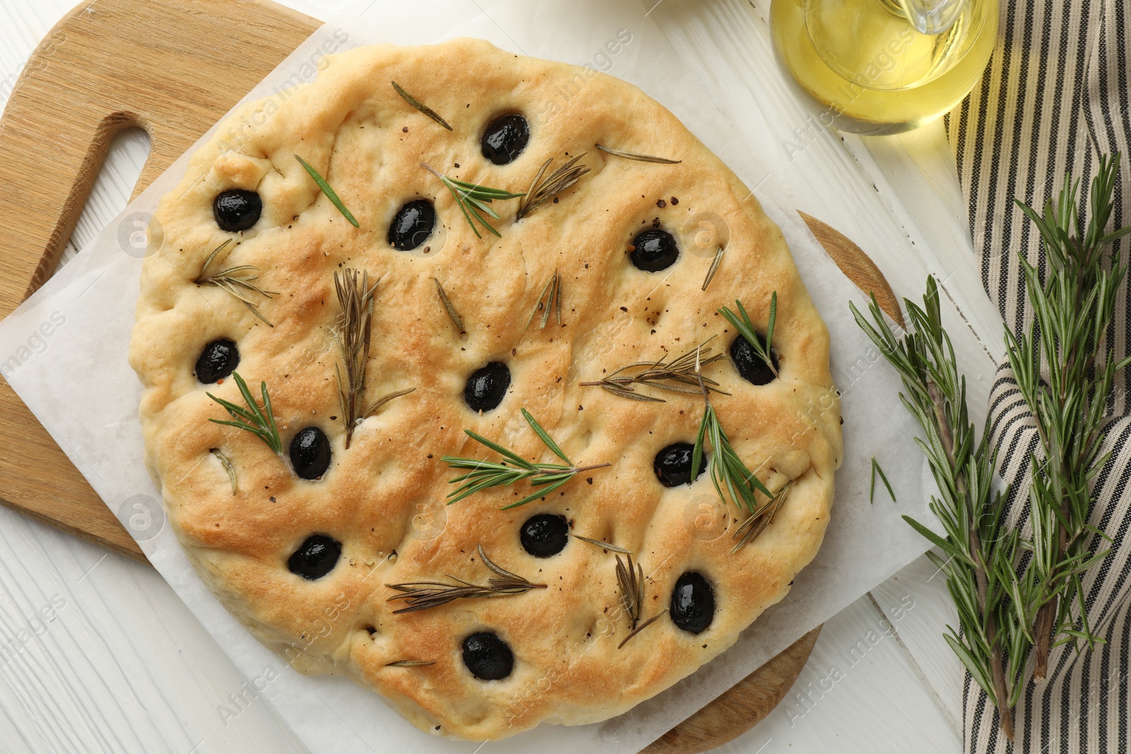 Photo of Delicious focaccia bread with olives, rosemary and oil on white wooden table, flat lay