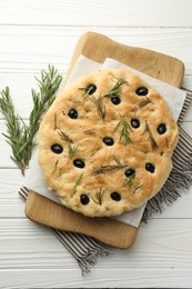 Photo of Delicious focaccia bread with olives and rosemary on white wooden table, top view