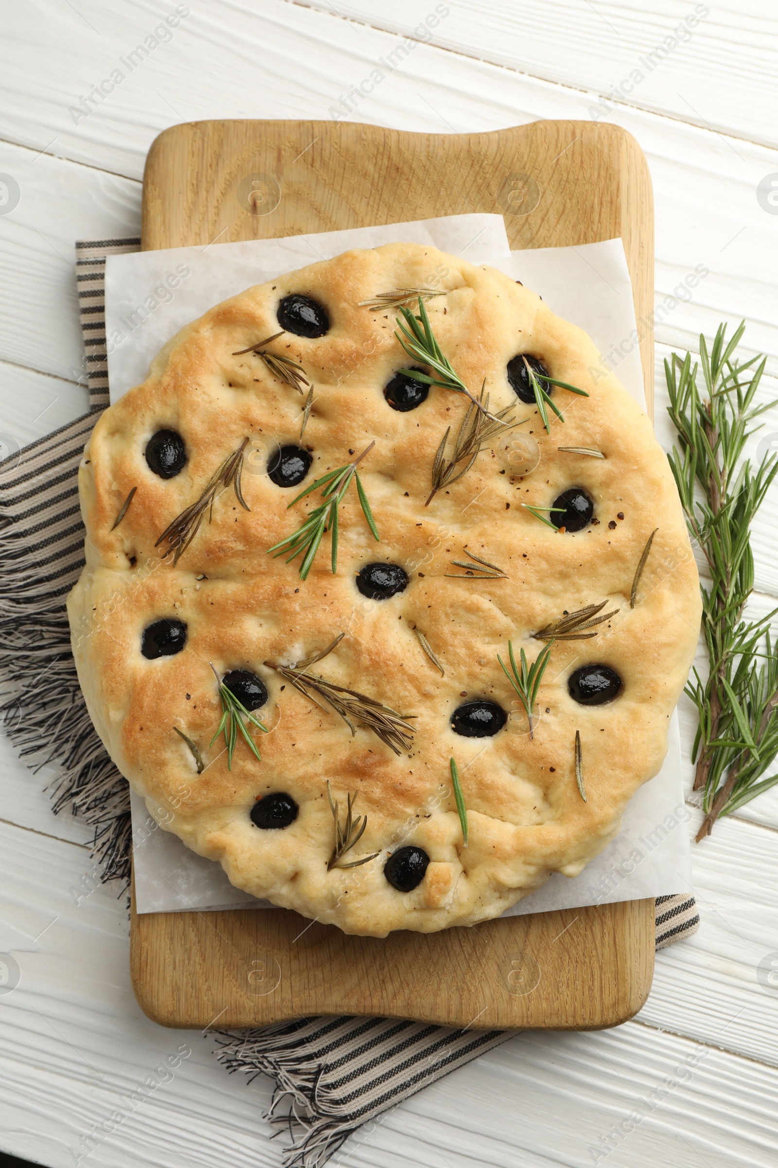 Photo of Delicious focaccia bread with olives and rosemary on white wooden table, top view