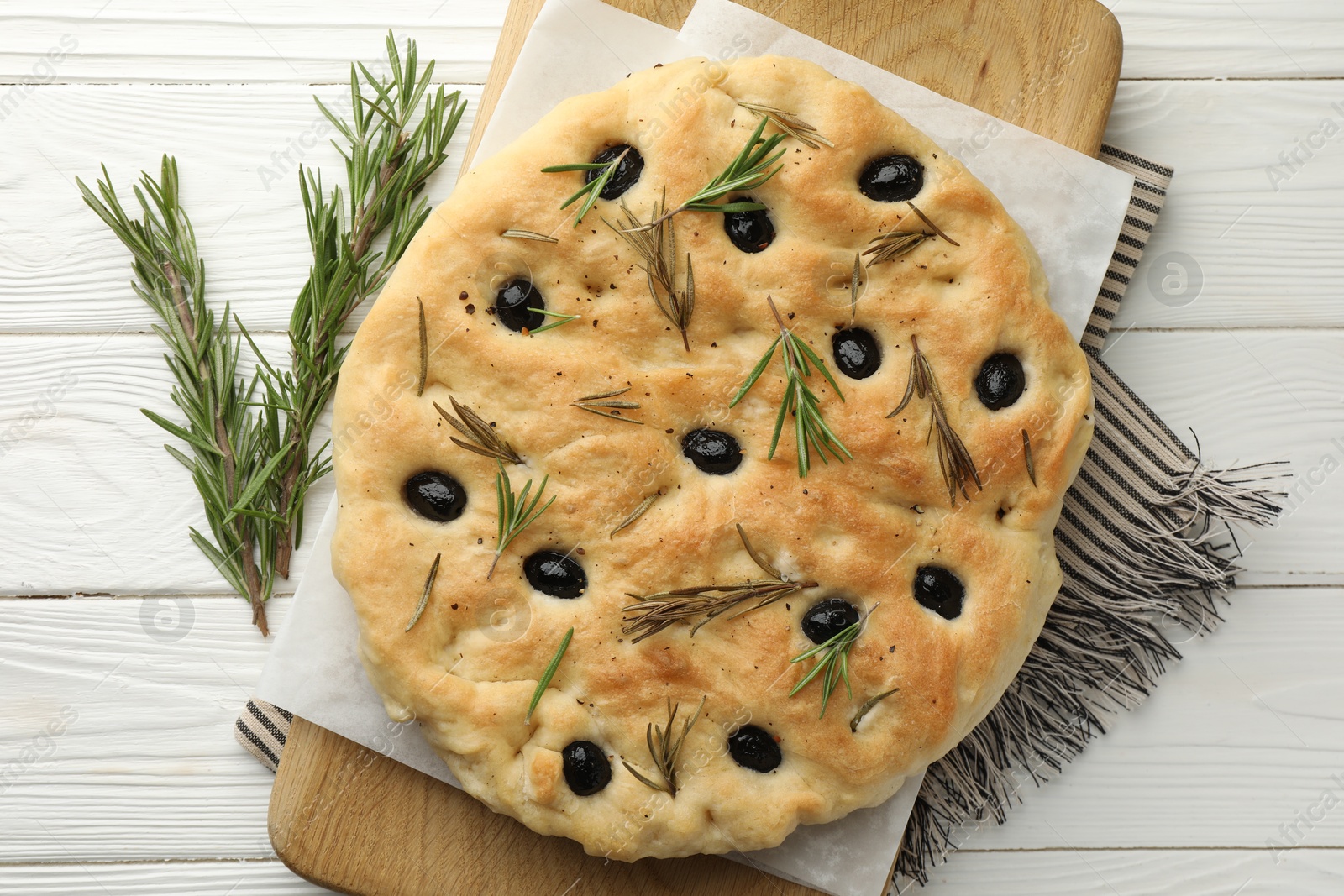 Photo of Delicious focaccia bread with olives and rosemary on white wooden table, top view