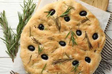 Photo of Delicious focaccia bread with olives and rosemary on white wooden table, top view