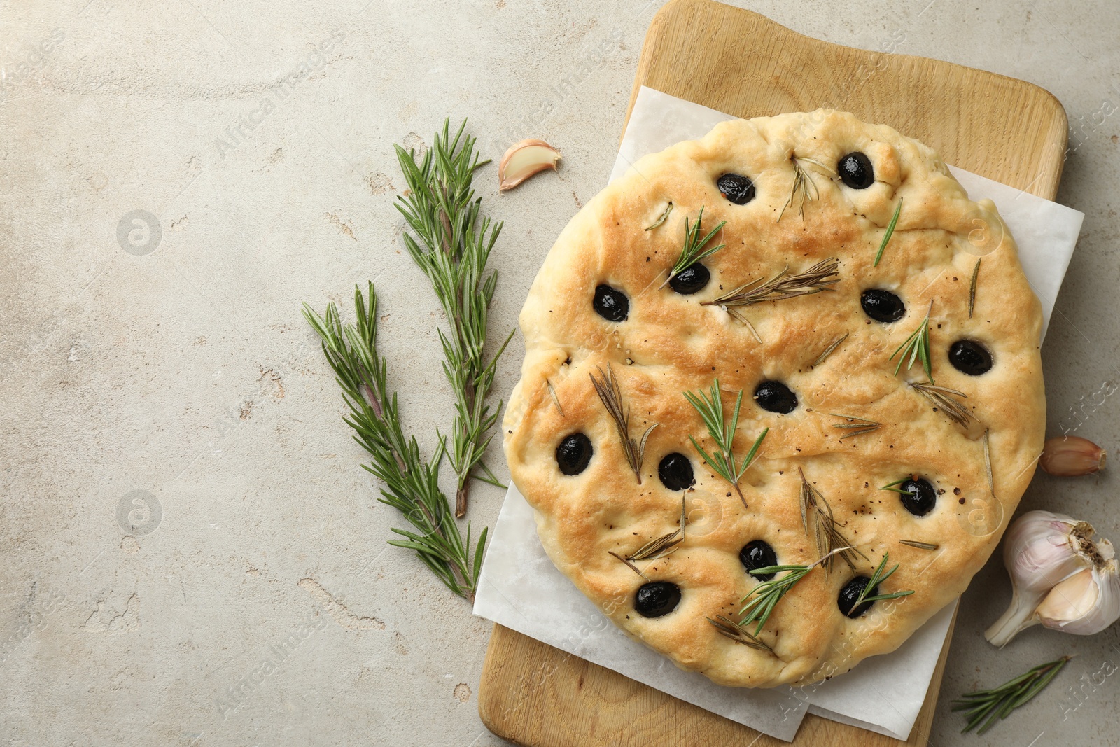 Photo of Delicious focaccia bread with olives, rosemary and garlic on grey table, flat lay. Space for text