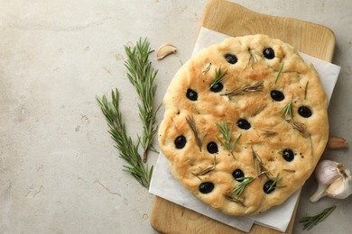 Photo of Delicious focaccia bread with olives, rosemary and garlic on grey table, flat lay. Space for text