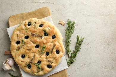 Photo of Delicious focaccia bread with olives, rosemary and garlic on grey table, flat lay. Space for text