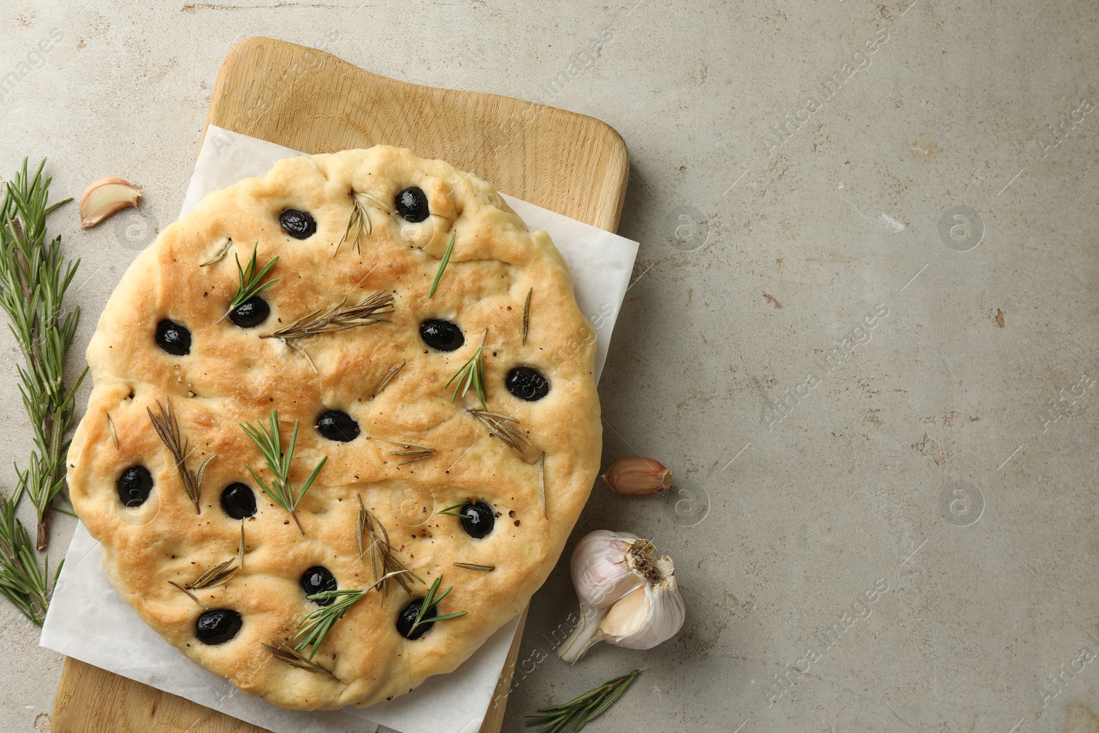 Photo of Delicious focaccia bread with olives, rosemary and garlic on grey table, flat lay. Space for text