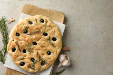 Photo of Delicious focaccia bread with olives, rosemary and garlic on grey table, flat lay. Space for text