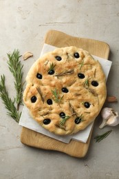 Photo of Delicious focaccia bread with olives, rosemary and garlic on grey table, flat lay