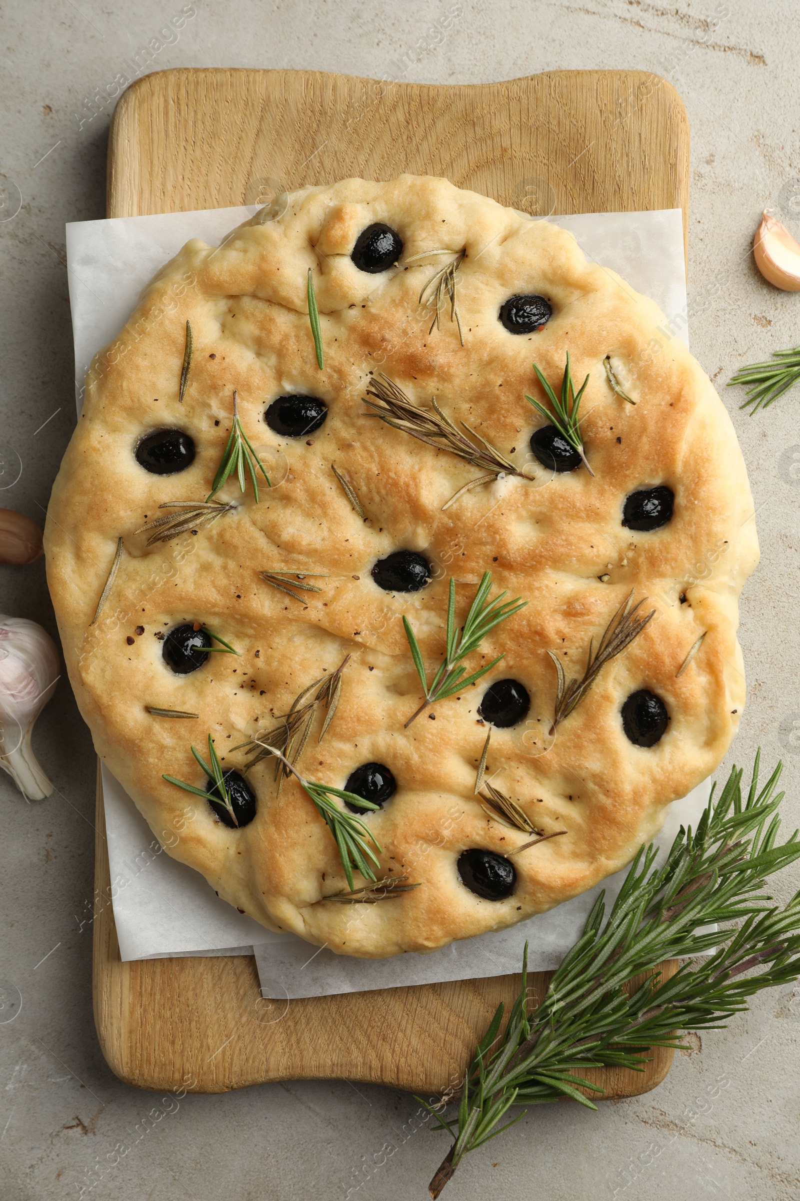 Photo of Delicious focaccia bread with olives, rosemary and garlic on grey table, flat lay