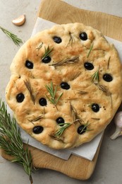 Photo of Delicious focaccia bread with olives, rosemary and garlic on grey table, flat lay