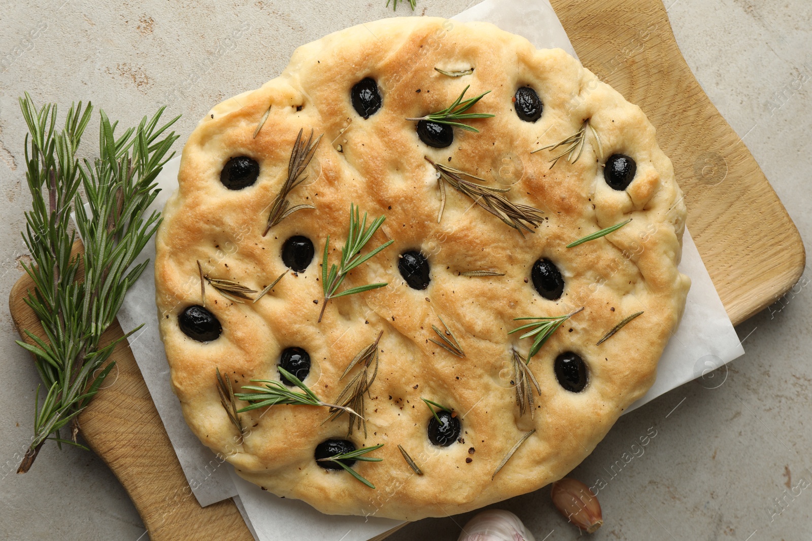 Photo of Delicious focaccia bread with olives, rosemary and garlic on grey table, top view