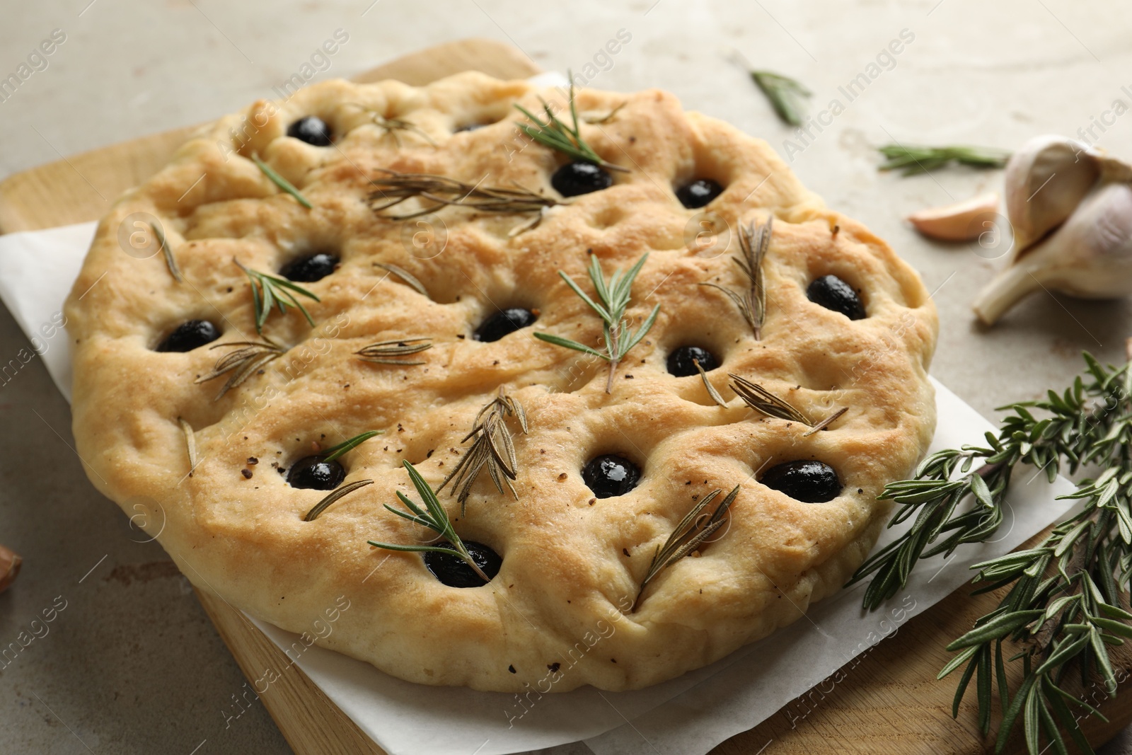 Photo of Delicious focaccia bread with olives, rosemary and garlic on grey table, closeup