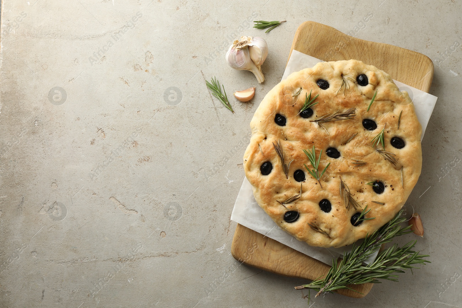 Photo of Delicious focaccia bread with olives, rosemary and garlic on grey table, flat lay. Space for text