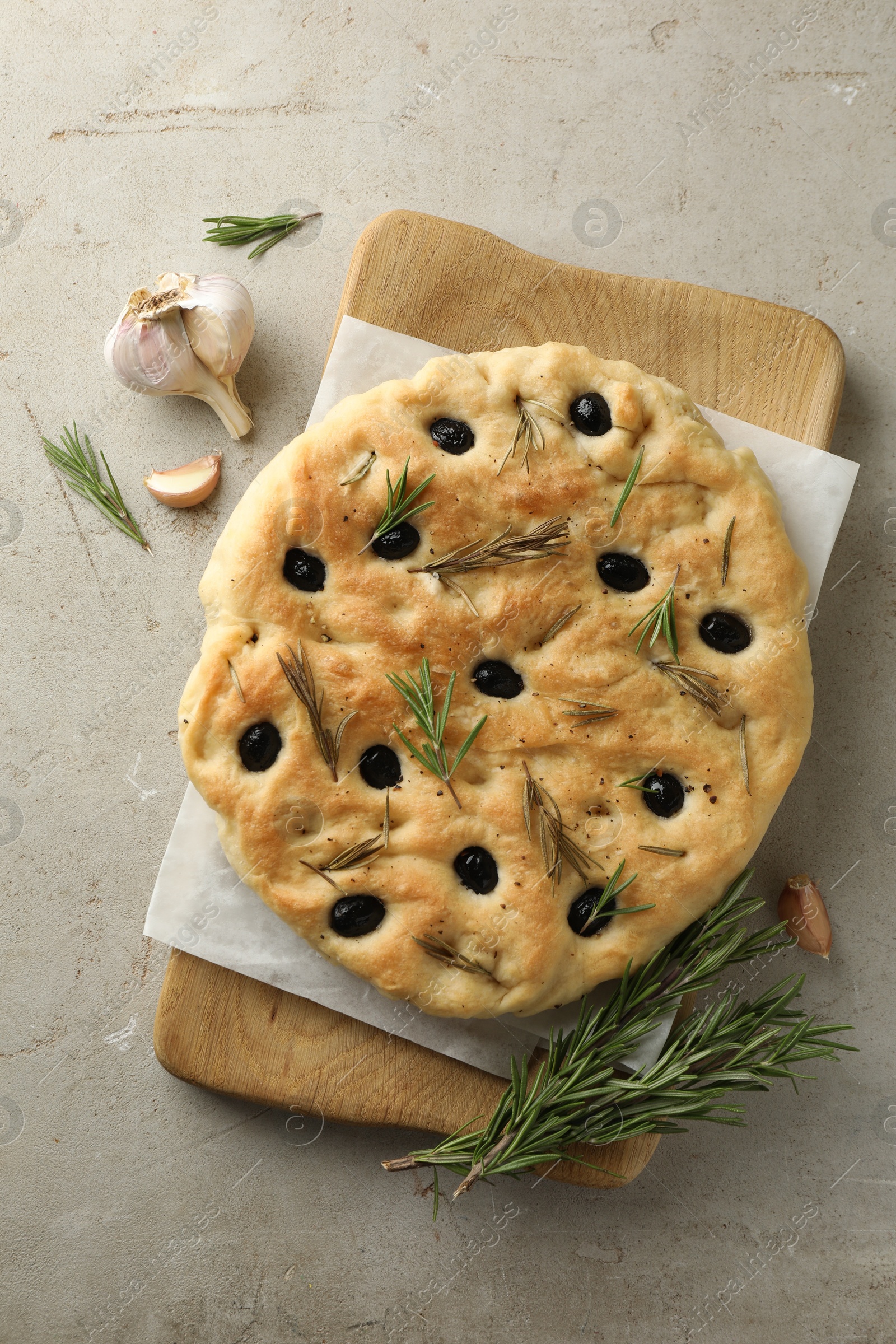 Photo of Delicious focaccia bread with olives, rosemary and garlic on grey table, flat lay