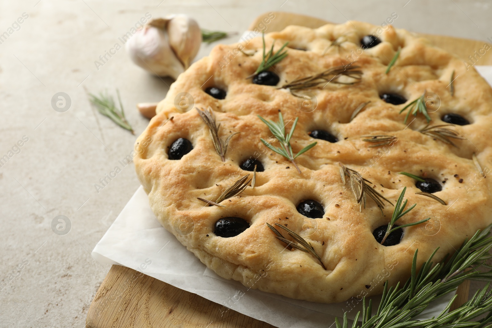 Photo of Delicious focaccia bread with olives, rosemary and garlic on grey table, closeup