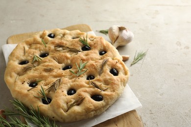 Photo of Delicious focaccia bread with olives, rosemary and garlic on grey table, closeup. Space for text