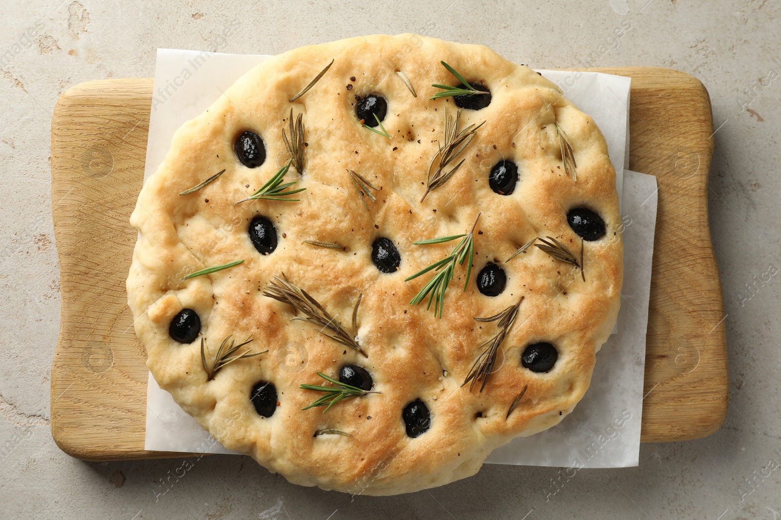 Photo of Delicious focaccia bread with olives and rosemary on grey table, top view