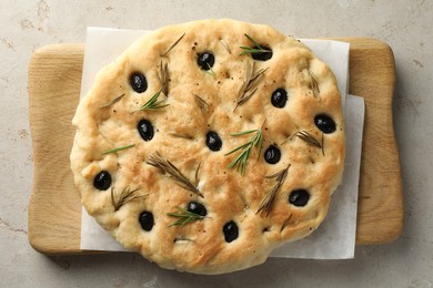 Photo of Delicious focaccia bread with olives and rosemary on grey table, top view