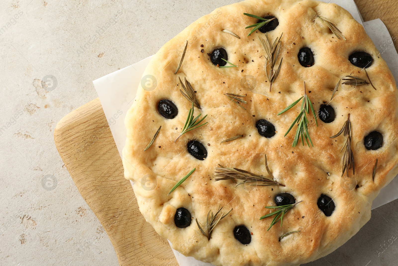 Photo of Delicious focaccia bread with olives and rosemary on grey table, top view