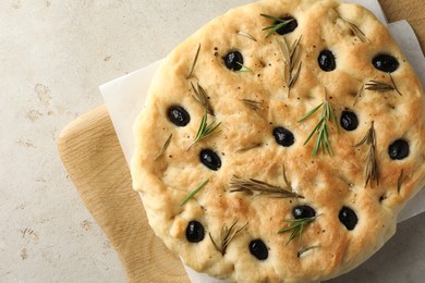 Photo of Delicious focaccia bread with olives and rosemary on grey table, top view