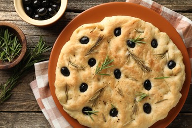 Photo of Delicious focaccia bread with olives and rosemary on wooden table, flat lay