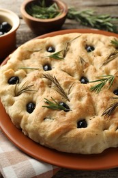 Photo of Delicious focaccia bread with olives and rosemary on table, closeup