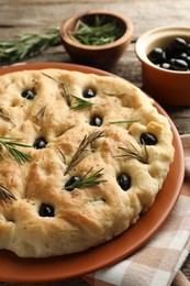 Photo of Delicious focaccia bread with olives and rosemary on table, closeup