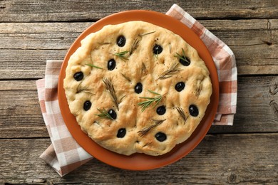 Photo of Delicious focaccia bread with olives and rosemary on wooden table, top view