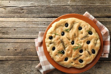 Photo of Delicious focaccia bread with olives and rosemary on wooden table, top view. Space for text