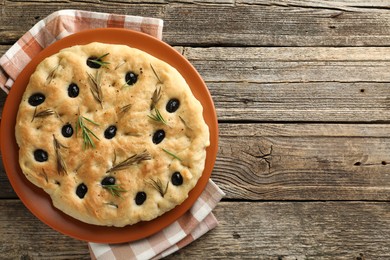 Photo of Delicious focaccia bread with olives and rosemary on wooden table, top view. Space for text