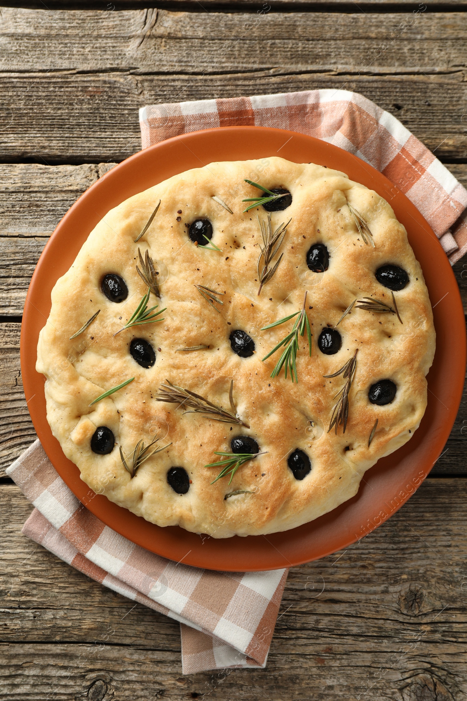 Photo of Delicious focaccia bread with olives and rosemary on wooden table, top view