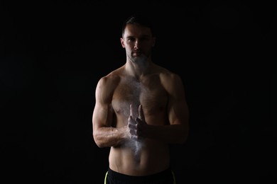 Photo of Man clapping hands with talcum powder before training on black background